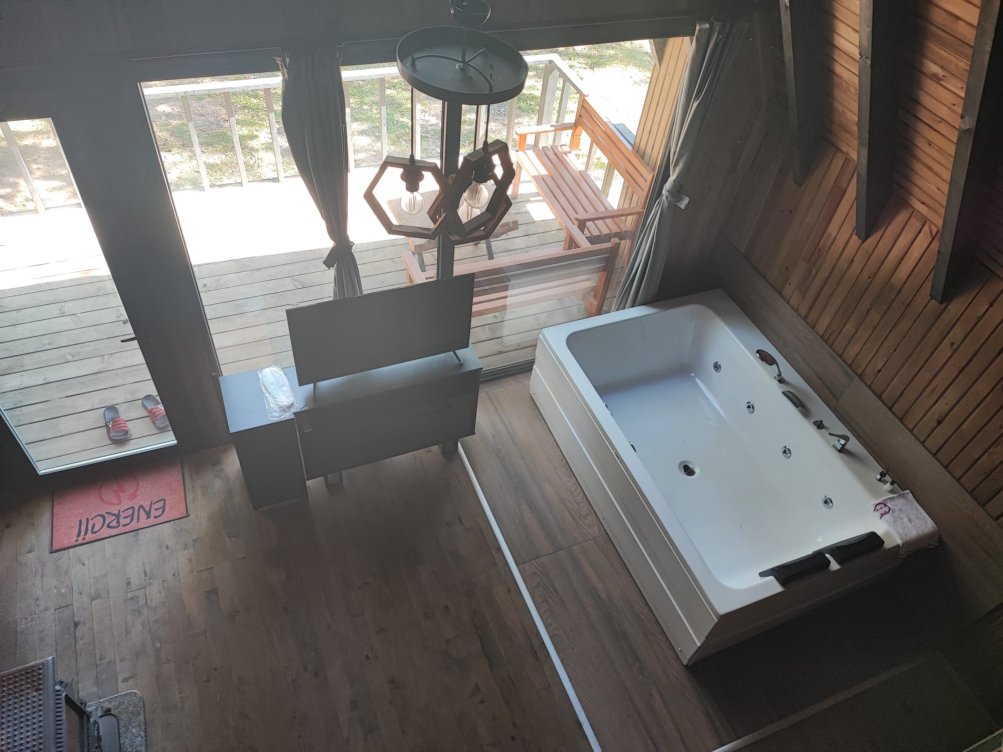 Overhead view of the private jacuzzi tub set beside sliding glass doors to the deck, lit by hexagon pendant lights.